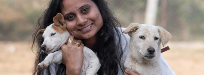 a woman snuggling with two cute rescued dogs