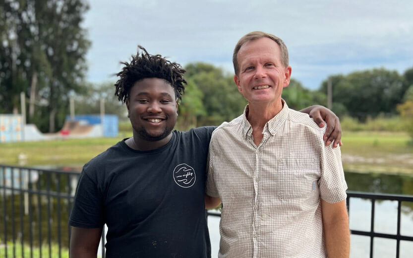 a teen boy with his arm around the shoulder of the program director
