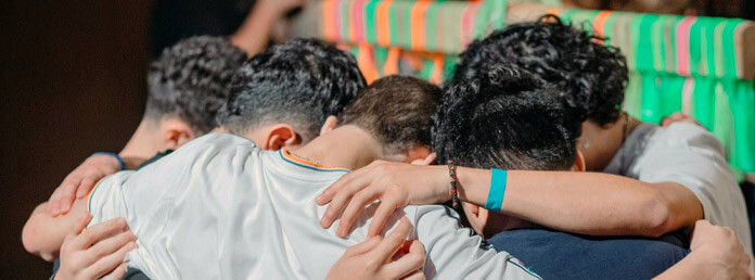 a group of teen boys huddle to pray