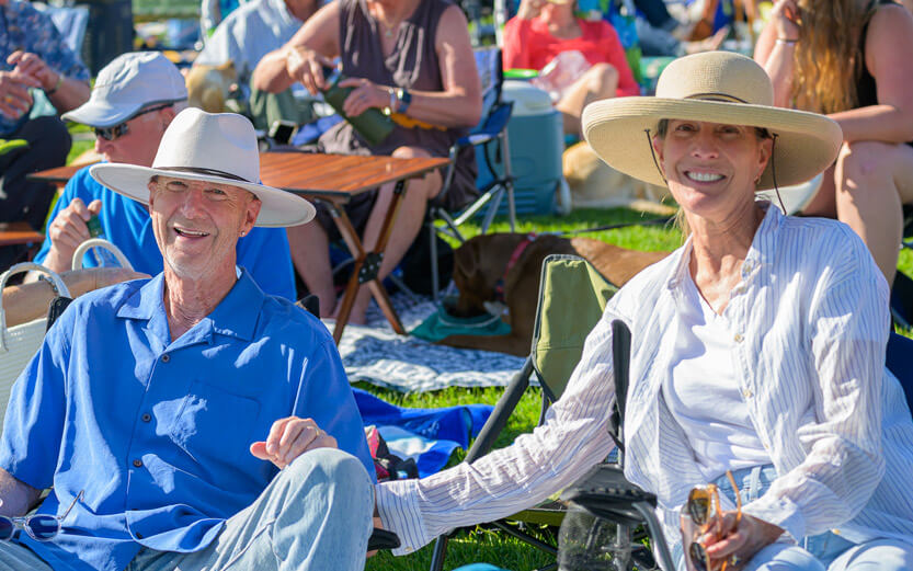couple wearing hats sitting in lawn chairs smiling