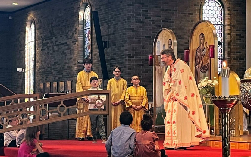 a church leader in a ceremonial robe speaking to young children