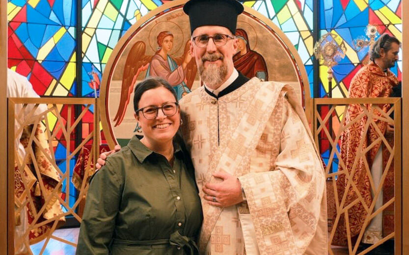 a man wearing a ceremonial robe with his arm around a woman as they pose for a photo