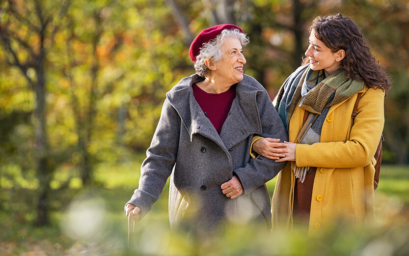 Young woman in park wearing winter clothing walking with her grandmother