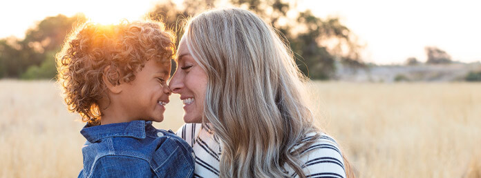 a mother and son touching noses and smiling