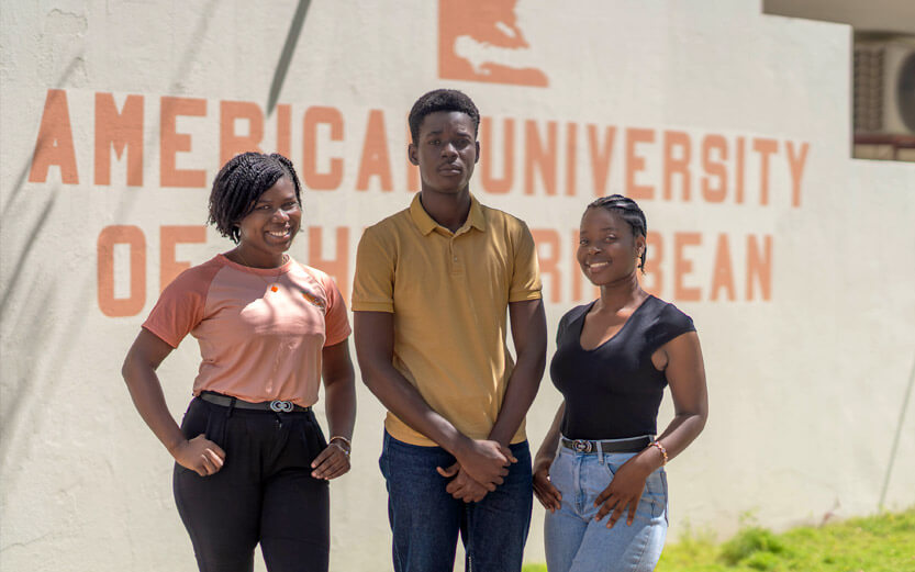 three students standing outside a school building