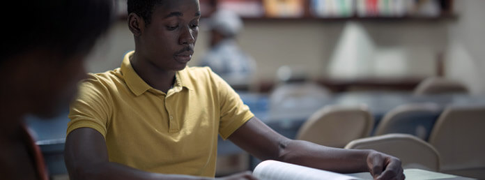 student wearing a yellow shirt studying at a desk