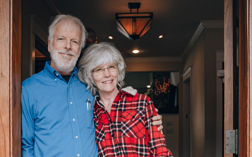 gray-haired couple standing in doorway smiling