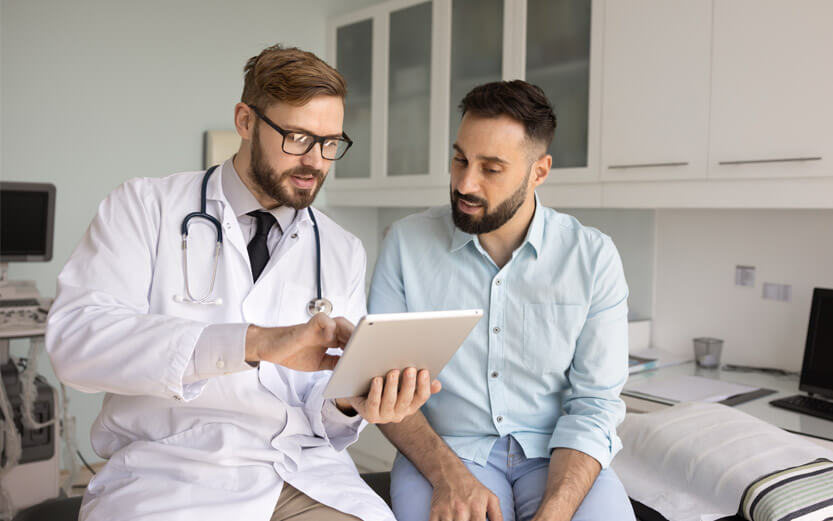 a patient talking to his doctor who is showing him something on his tablet
