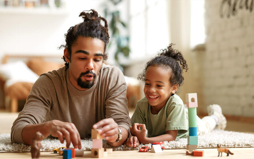 a father playing with blocks on the floor with his child
