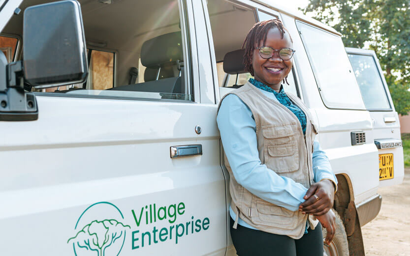 Village Enterprise worker leaning against a van