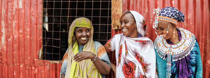 three women in front of a red wall smiling