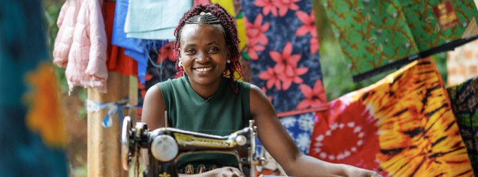 woman seated at a sewing machine with textiles behind her