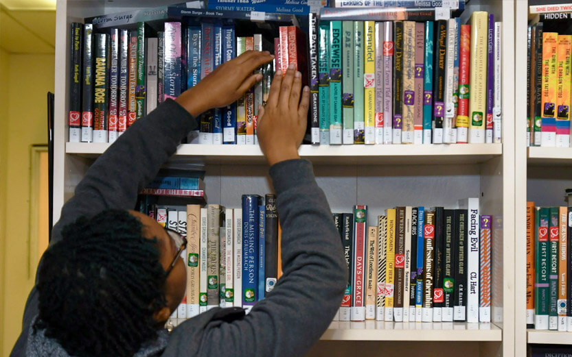 a young adult searching through library shelves