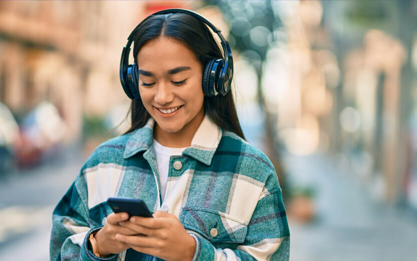 a young woman walking and listening to music on her headphones