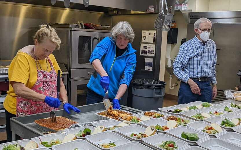 three members of the church preparing meals to be donated