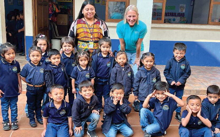a group of young children in blue shirts posing for a photo with their teacher
