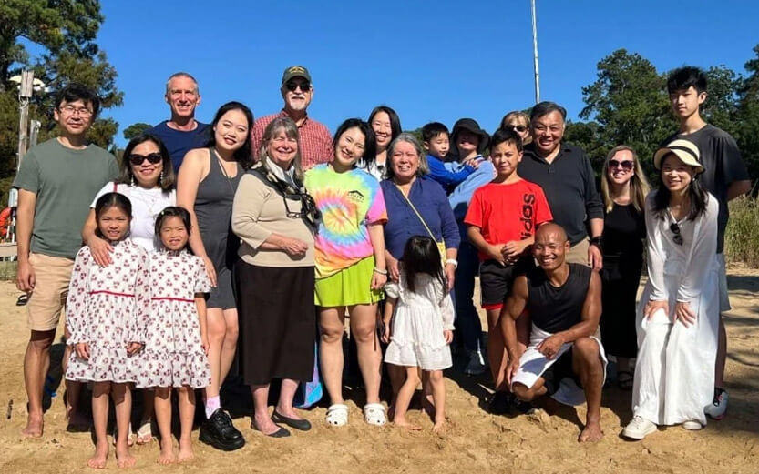 a group of adults and children posing for a photo outside
