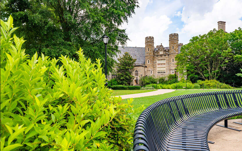 a WCU stone building with a curved metal bench in the foreground