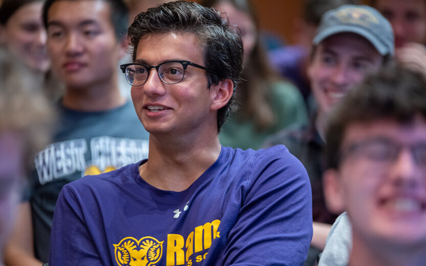 close up of a student in a classroom wearing glasses and smiling