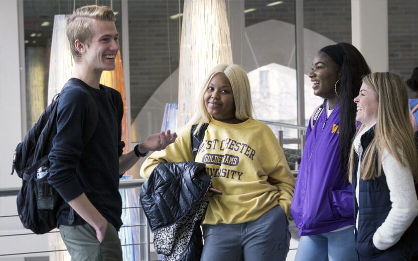 a group of four students talking and laughing