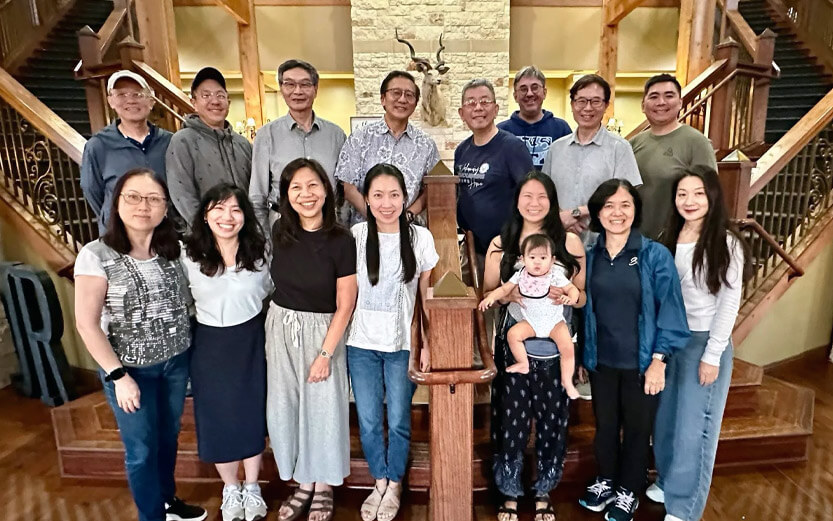 a group of people at the foot of a double staircase smiling