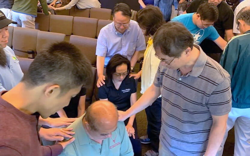 members of the church putting healing hands on the shoulders of other members