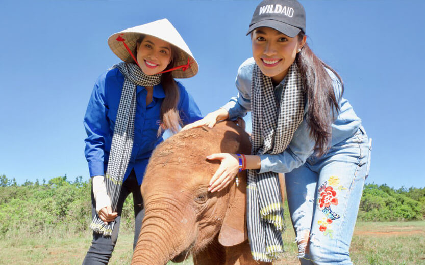two women with a baby elephant