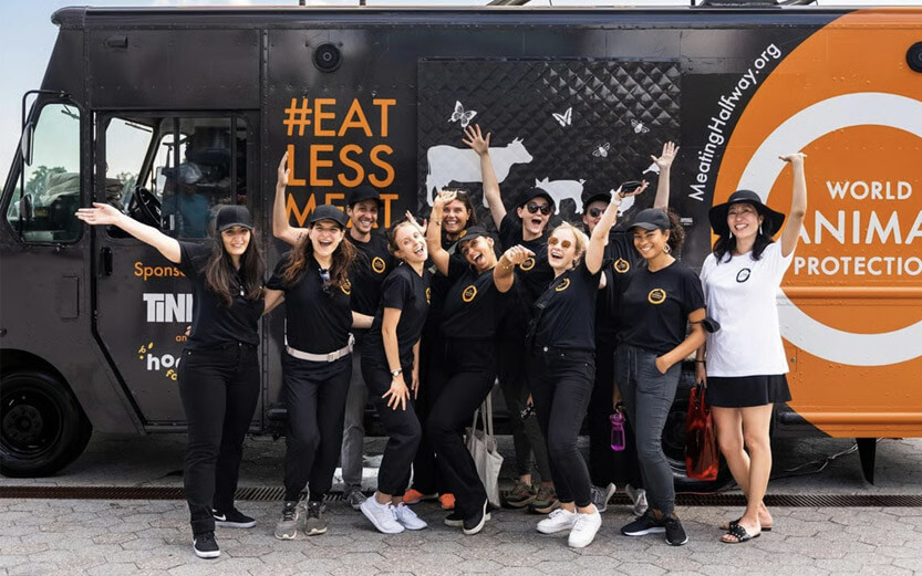 a group of people in front of a truck spreading the word to Eat Less Meat