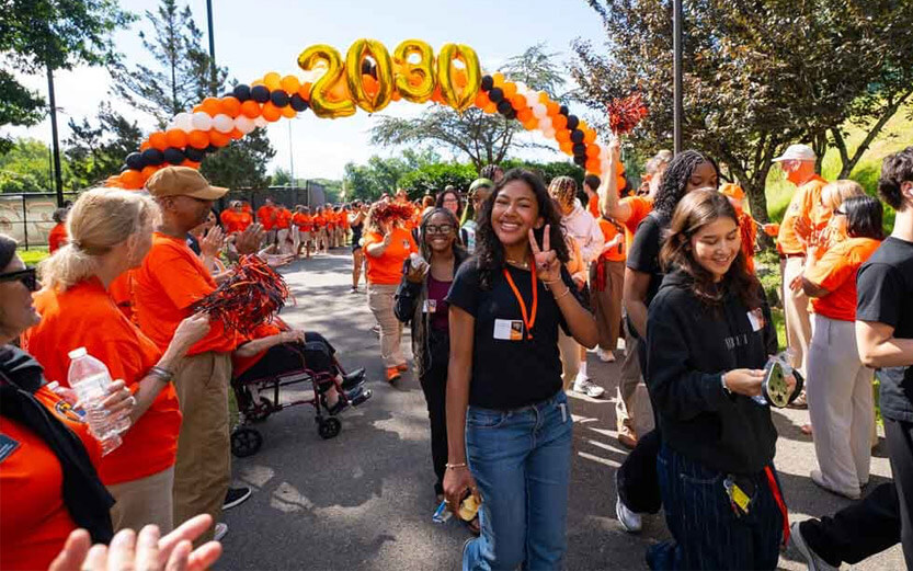 students walking under a balloon banner with 2030 in gold balloons