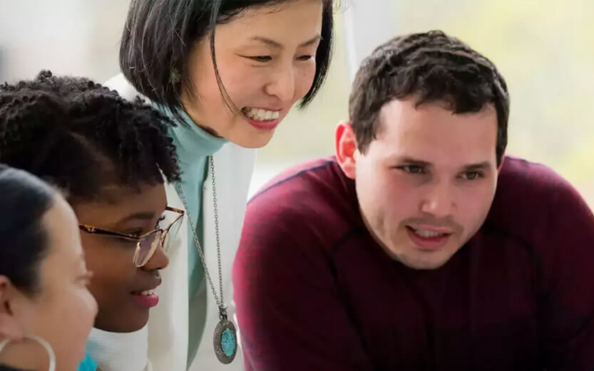 students and professor looking at a computer screen