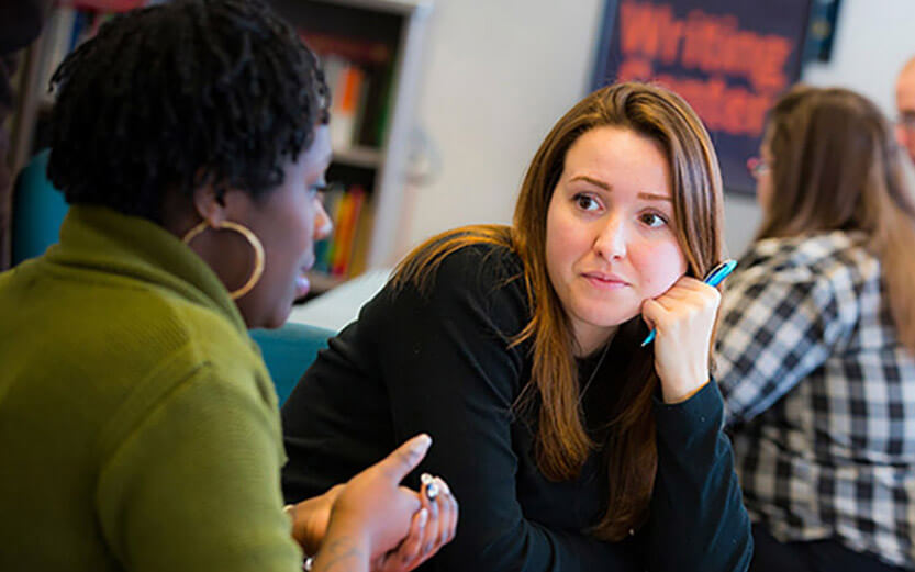 two students having a conversation in a study hall