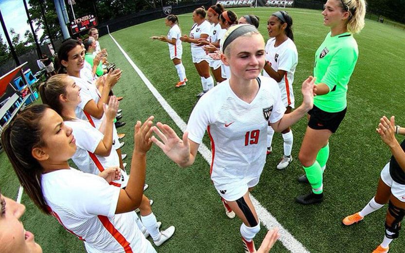 the women's soccer team in uniform clapping for each other