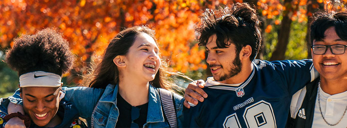four students walking and laughing outdoors