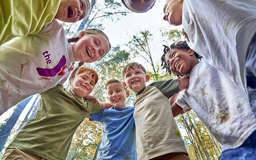 a group of kids smiling in a huddle outside